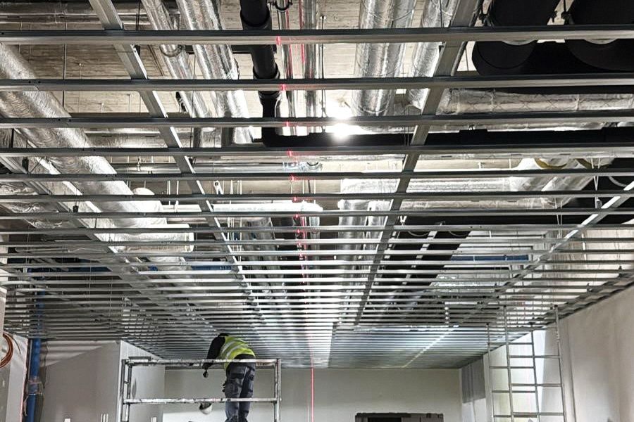 Stalowy ruszt sufitu podwieszanego z kanałami wentylacyjnymi i czerwonymi liniami lasera krzyżowego